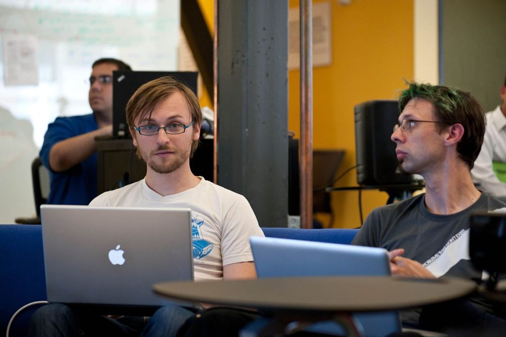 A programmer reviewing lines of code on a large monitor in a dim office.